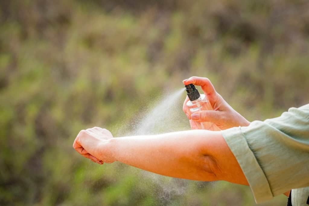 a traveler applying insect repellent to prevent malaria transmission while traveling abroad