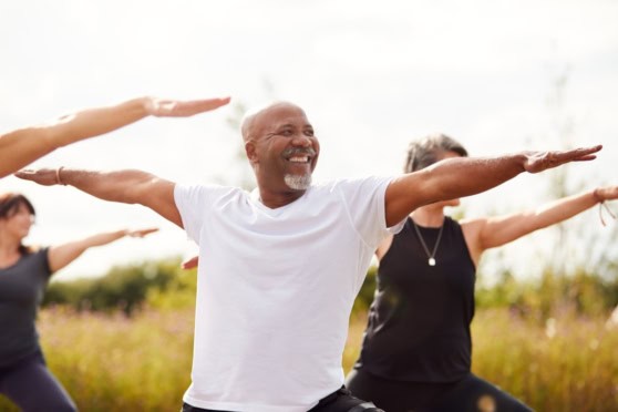 Diverse group practicing outdoor yoga for health and wellness at sunrise, promoting outdoor exercise and healthy lifestyle choices for global citizens.