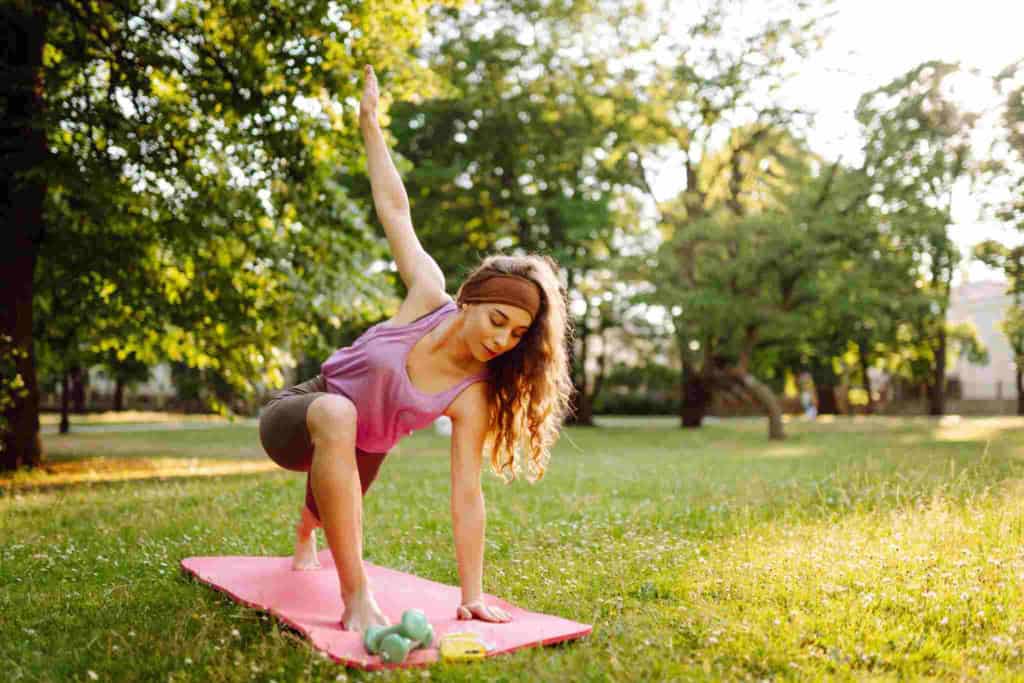a woman doing yoga in a park, as part of her plan for staying healthy while traveling