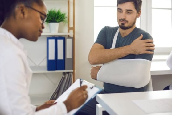 A young man with a shoulder injury consults a healthcare professional, seeking assistance and guidance for his medical condition in a clinical setting.
