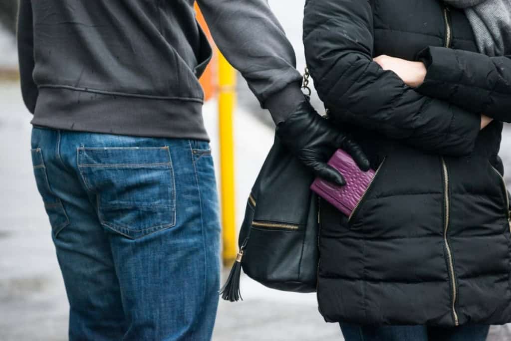 a pickpocket stealing a phone from a woman's coat pocket