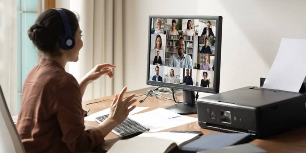 A woman participating in a virtual meeting, engaging with colleagues on a computer screen, representing professional communication and remote work connectivity.