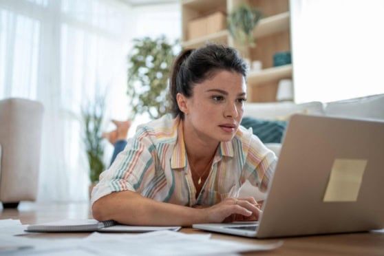 Young woman researching international health insurance options at home.