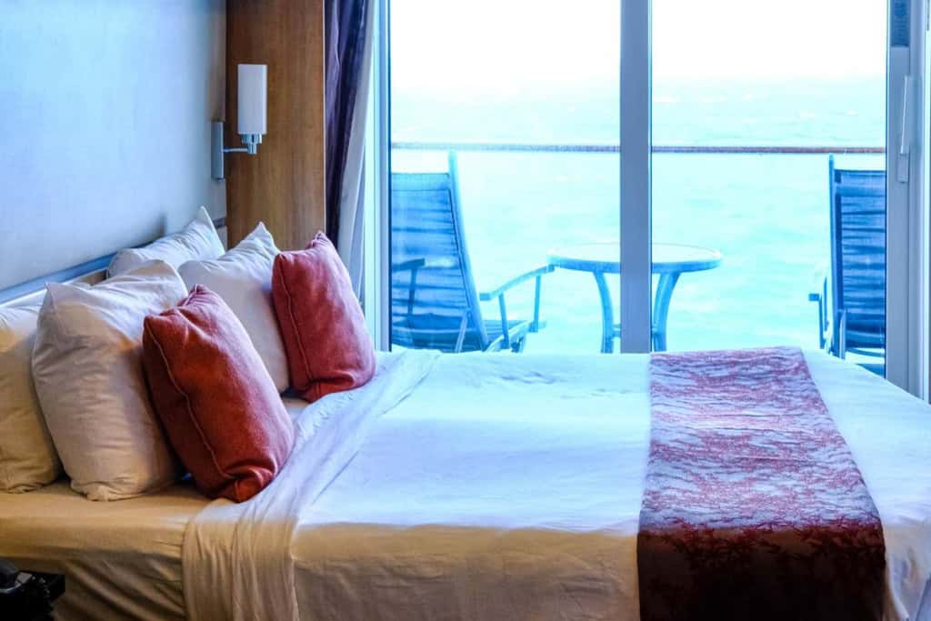 a bedroom on a cruise liner, with a window showing the horizon; one of the best cruise tips to avoid seasickness