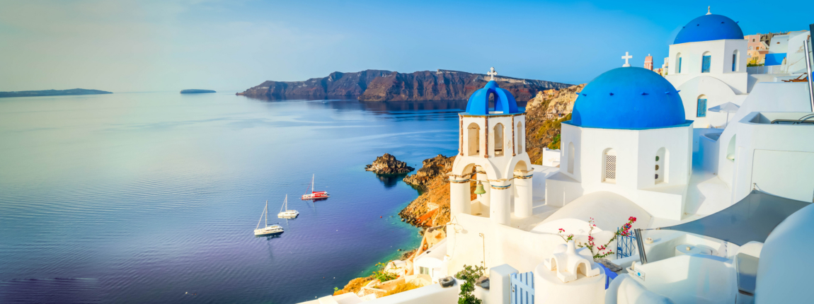 Beautiful sunset view of Santorini, Greece, with iconic white-washed buildings and blue-domed churches overlooking the Aegean Sea, showcasing travel, tourism, and Mediterranean architecture.