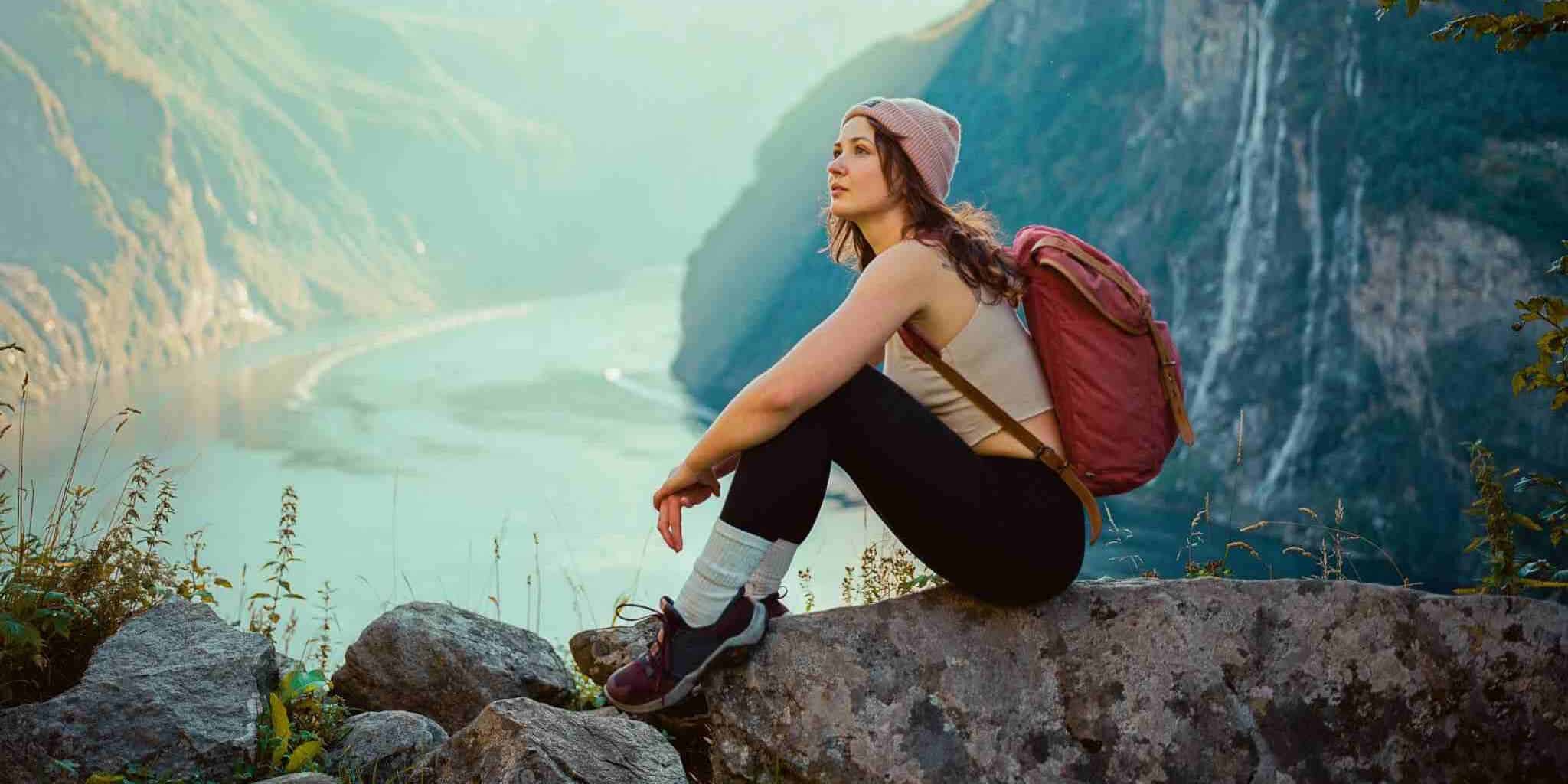 a solo female traveler sitting among mountains