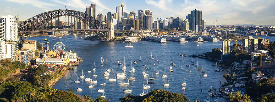 Sydney Harbour skyline with boats and the iconic Harbour Bridge, featuring high-rise buildings and a vibrant cityscape, ideal for ICI 2025 event imagery.