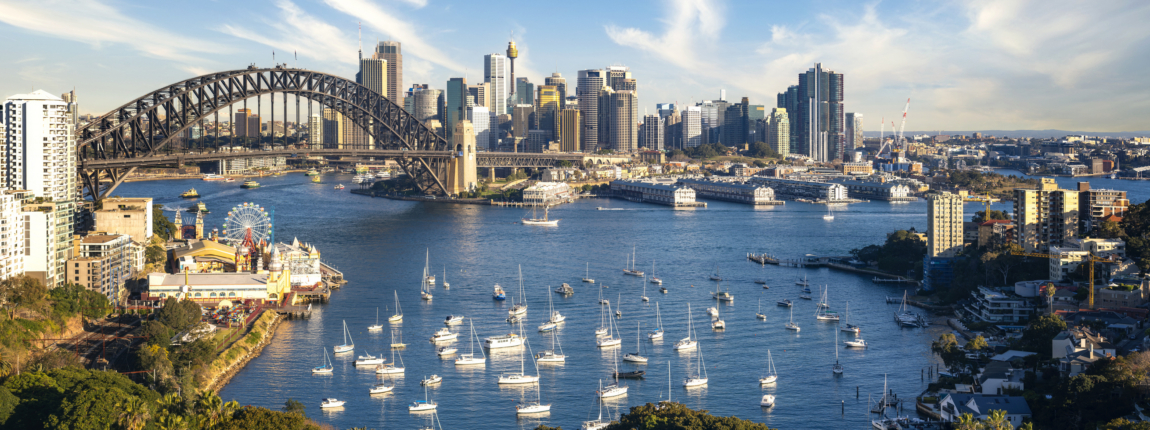 Sydney Harbour skyline with boats and the iconic Harbour Bridge, featuring high-rise buildings and a vibrant cityscape, ideal for ICI 2025 event imagery.