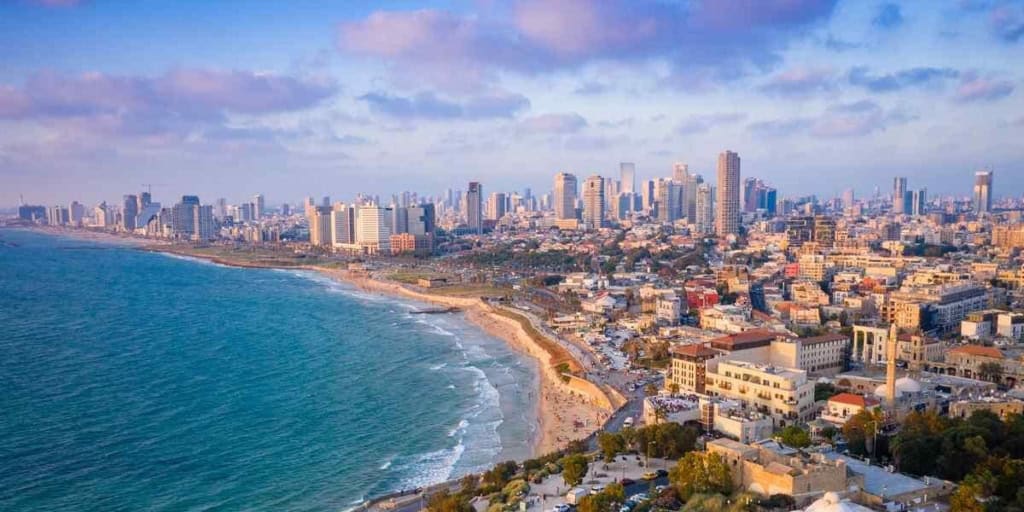 A panoramic view of San Diego's city skyline along the coastline with sandy beaches and ocean waves, ideal for international residents seeking reliable health insurance options.