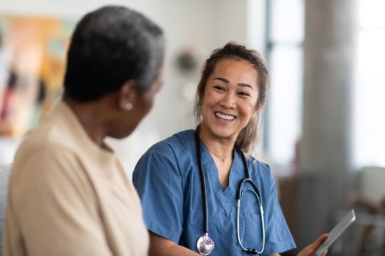 Friendly nurse with stethoscope smiling at patient, emphasizing care.