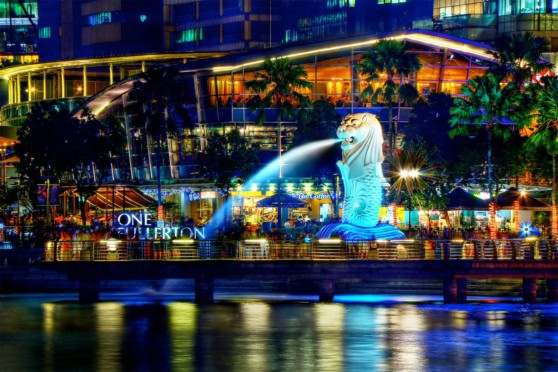 Vibrant night scene of Singapore's iconic Merlion statue with colorful city lights reflecting on the water, highlighting urban life and tourism.