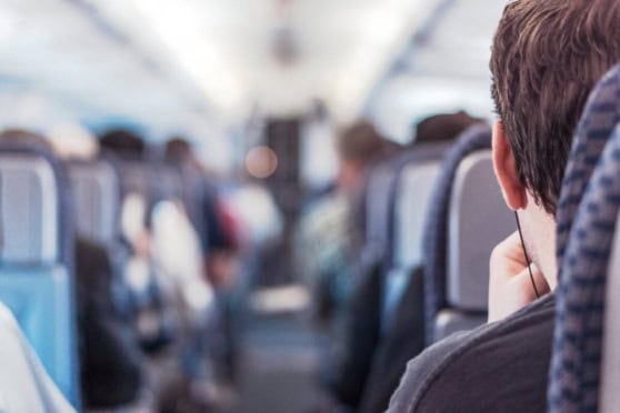 A traveler with headphones seated on an airplane, highlighting the importance of international insurance coverage for global travelers.