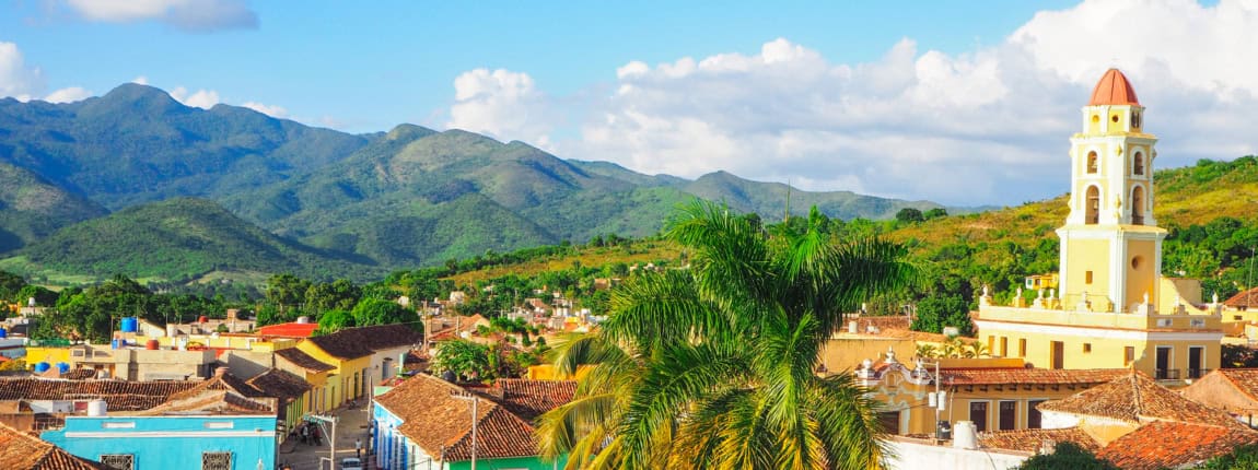 Vibrant colorful town with Spanish colonial architecture set against lush green mountains Under a bright blue sky at ICI 2025 conference location in Mexico.