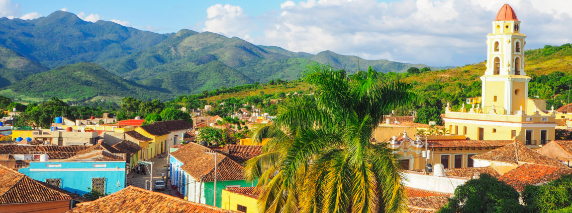 Vibrant colorful town with Spanish colonial architecture set against lush green mountains Under a bright blue sky at ICI 2025 conference location in Mexico.