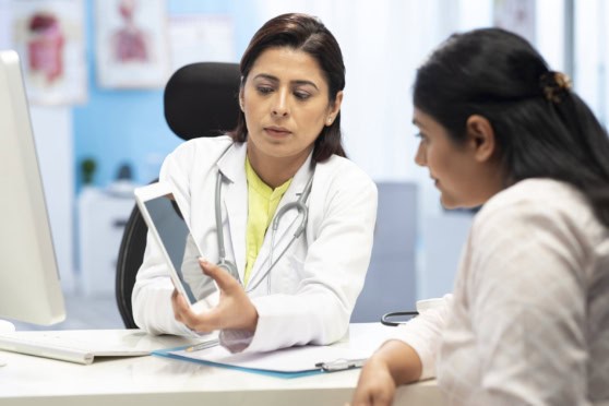 Doctor consulting a patient in a medical office setting; healthcare, insurance, international medical coverage, professional medical advice, patient care, medical consultation.
