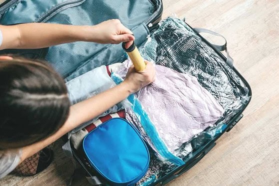 ALT text: A person packing a suitcase with clothes and travel essentials for international travel preparation.