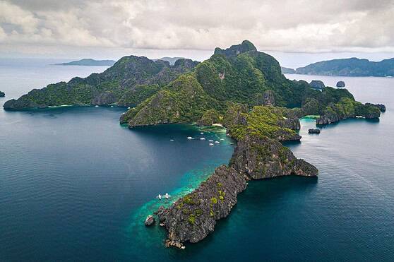 Aerial view of a green island surrounded by blue ocean, emphasizing travel, adventure, and resort destinations.