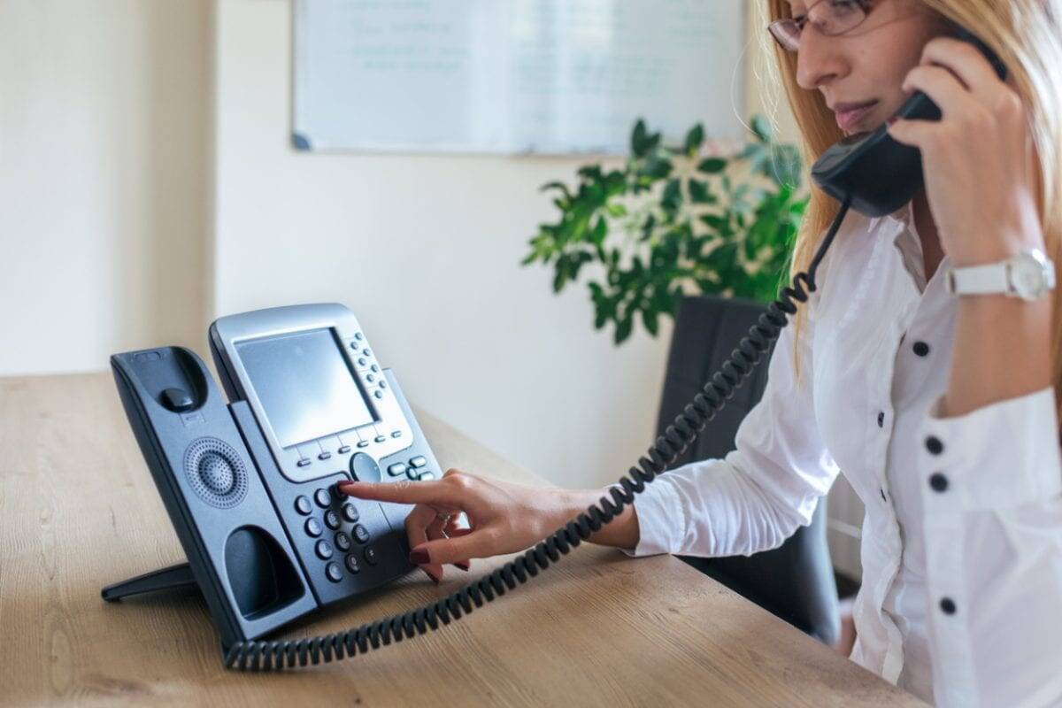 a business woman making a call on a landline phone using our international calling codes list
