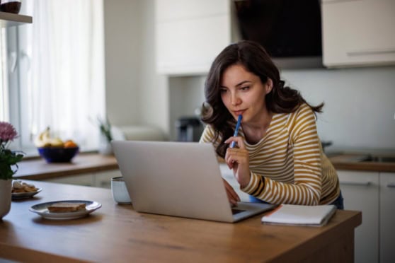 A woman researching international health insurance options on her laptop at home for global health coverage needs.