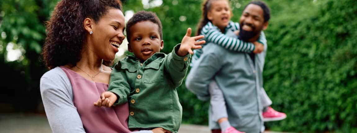 Family outdoor walk with smiling parents and children, capturing joyful moments in nature.
