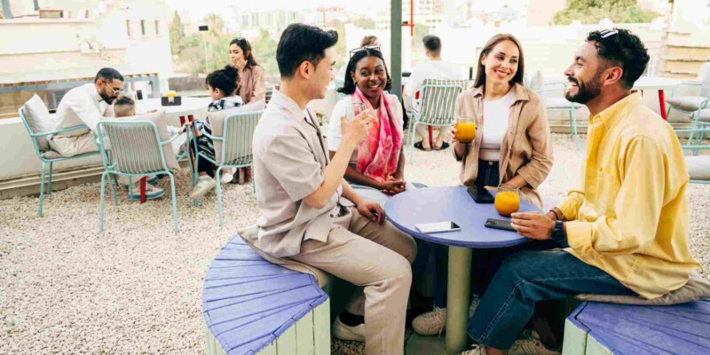 a group of international friends drinking together on a rooftop, prompting the question of what is the difference between an expat vs immigrant