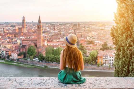 Inspiring travel scene of a woman enjoying a scenic view of a historic European city, symbolizing global travel insurance options for international citizens.