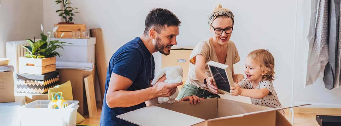 A cheerful family unpacking their belongings in a new home, emphasizing the importance of international health coverage when relocating abroad.