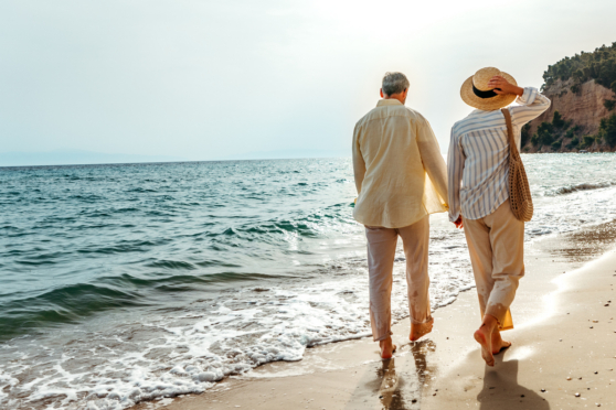 Relaxing seniors strolling by the ocean, capturing the essence of carefree seaside leisure with natural beauty and tranquil waters.