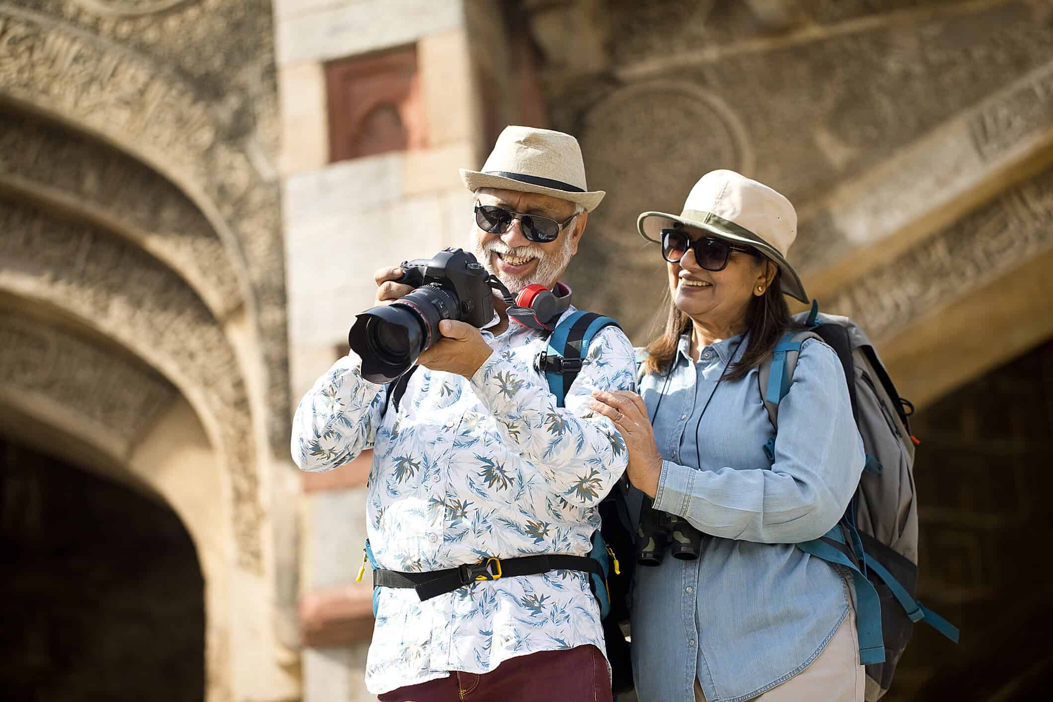Elderly couple exploring historic site with photography equipment during travel.