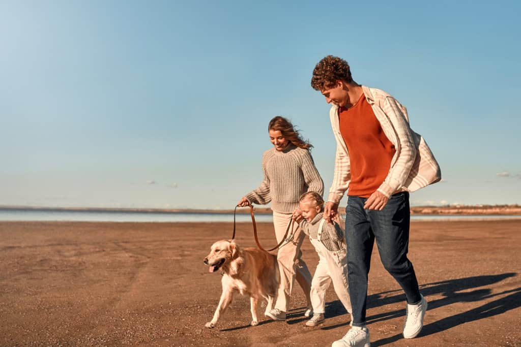 Family walking with dog on beach, representing international travel insurance and family health coverage.