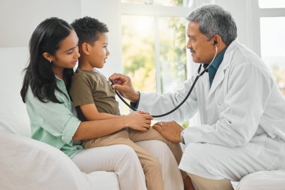 Young boy visiting doctor with his mother, receiving a checkup in a well-lit, modern clinic setting.