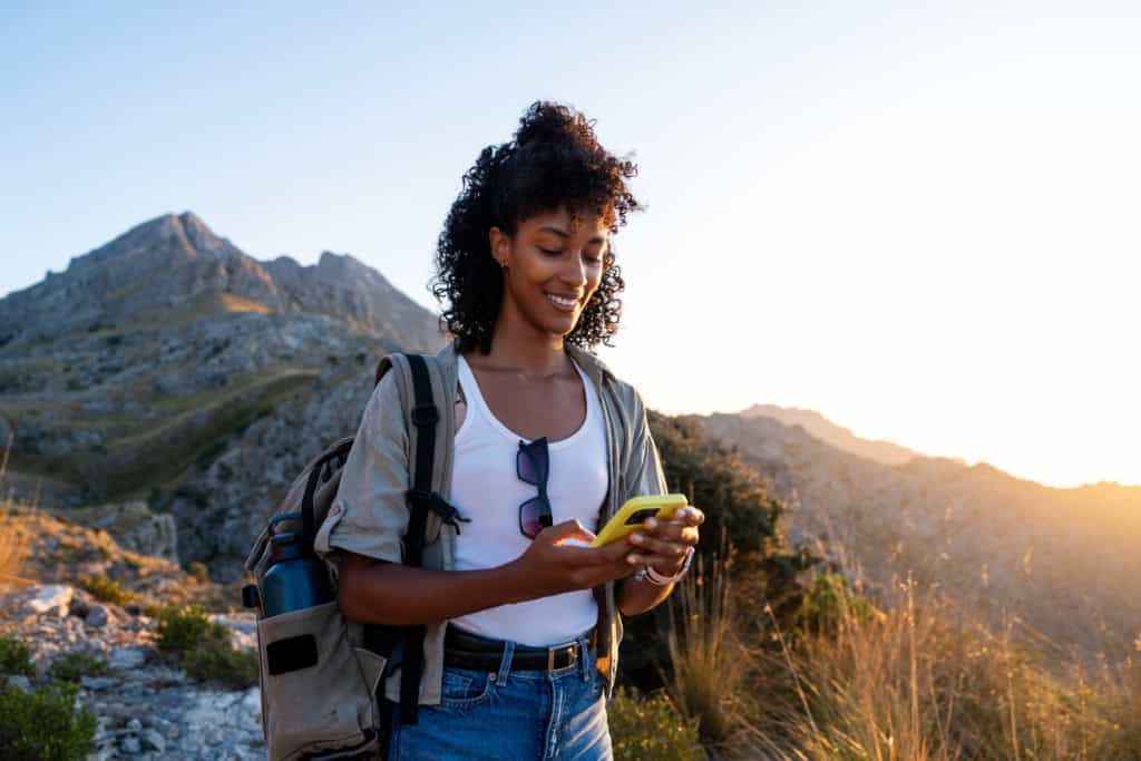 Female tourist using her smartphone during a mountain hike