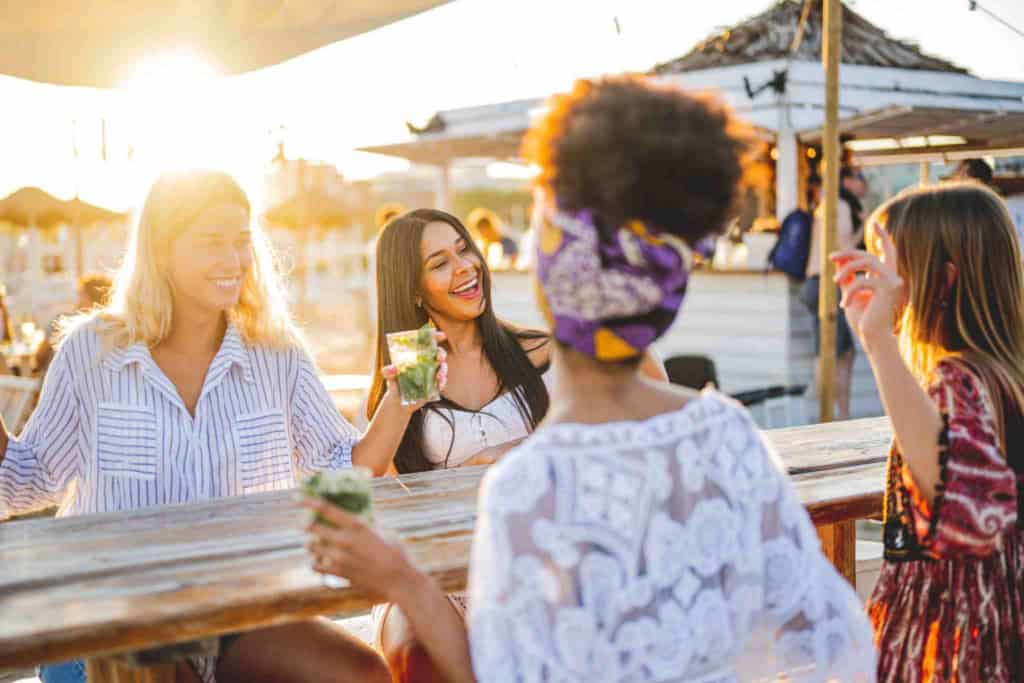 a group of female friends drinking in the sun, showing how making new friends can help you adapt to living in a new country