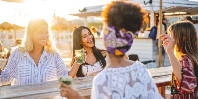 a group of female friends drinking in the sun, showing how making new friends can help you adapt to living in a new country