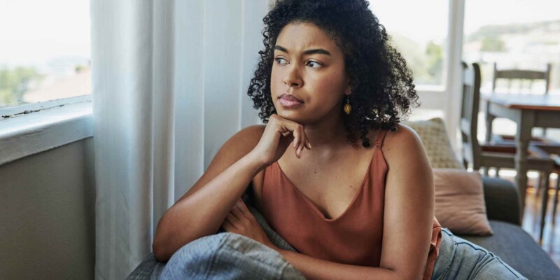 a lonely woman looking out the window, feeling isolated as she deals with reverse culture shock after returning home from abroad
