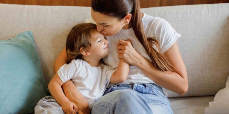 a mother comforting her young son on a sofa, showing one of the ways you can help your child adjust to life abroad