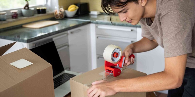 a teenage boy packing a box, indicating a family moving abroad with children