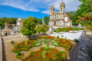 Historic church with colorful flower garden and blue sky.