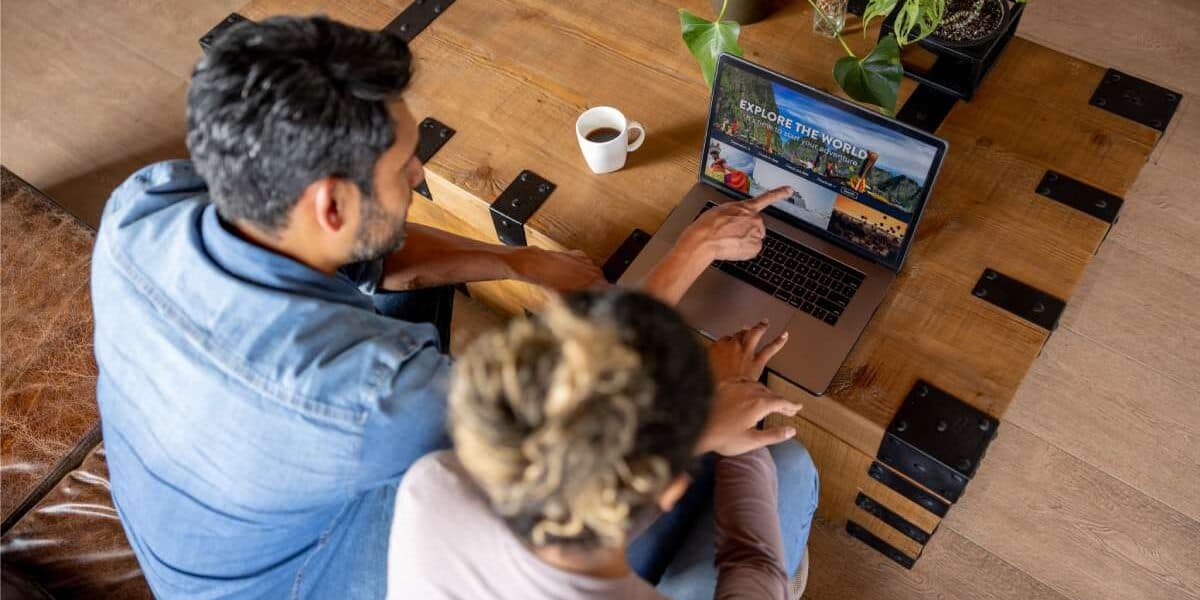 Alt text: Two people viewing international travel and health insurance options on a laptop, with a cup of coffee nearby, promoting global coverage for expatriates.