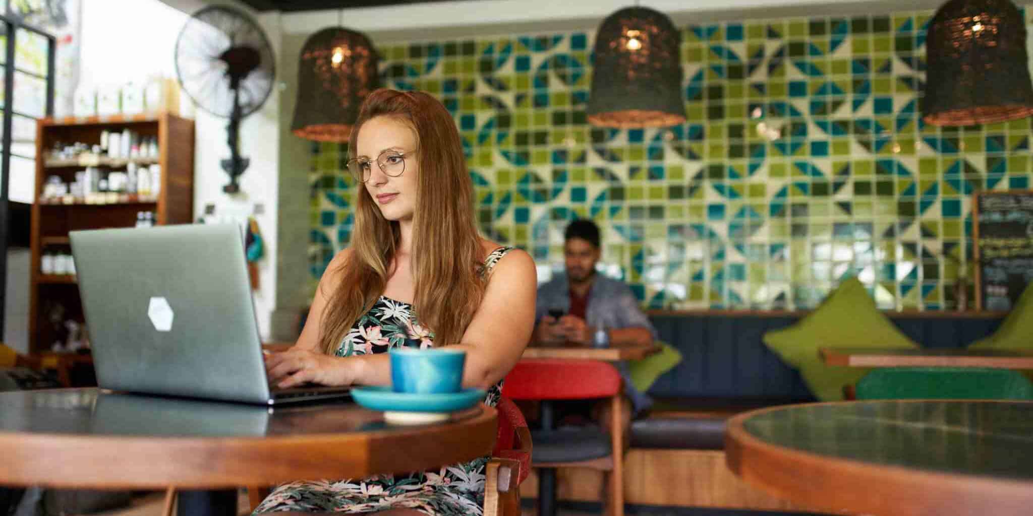 woman typing on a laptop sitting at a table in a cafe in Bali