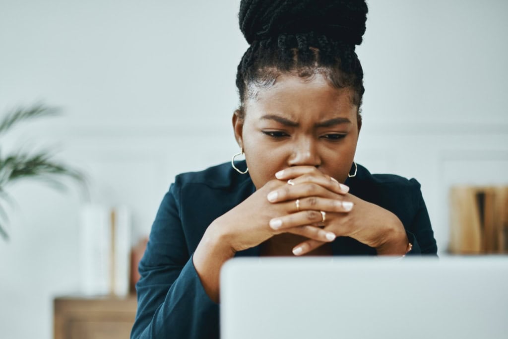 a woman frowning and looking concerned as she looks down at her laptop, reading safety tips for avoiding terrorism attacks