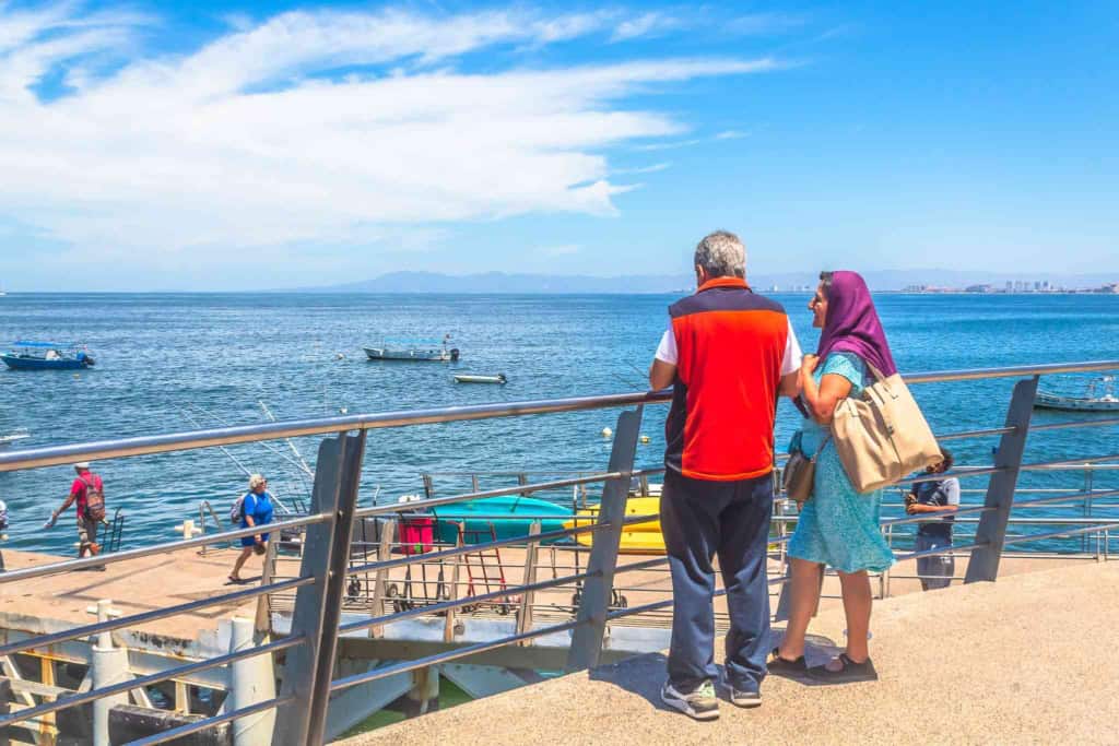 Meta description: An international traveler couple admiring a beautiful waterfront view, highlighting the need for reliable global health insurance and coverage options for international citizens.