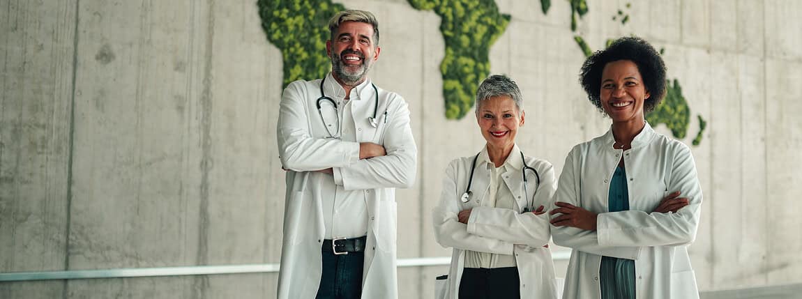 Diverse team of doctors standing confidently in a modern environment with a lush green world map background.