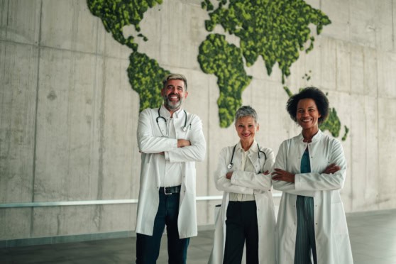 Diverse team of doctors standing confidently in a modern environment with a lush green world map background.