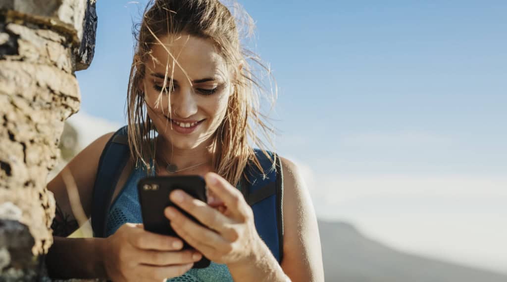 a happy woman looking at her phone during a trip around the world where she learns valuable travel lessons