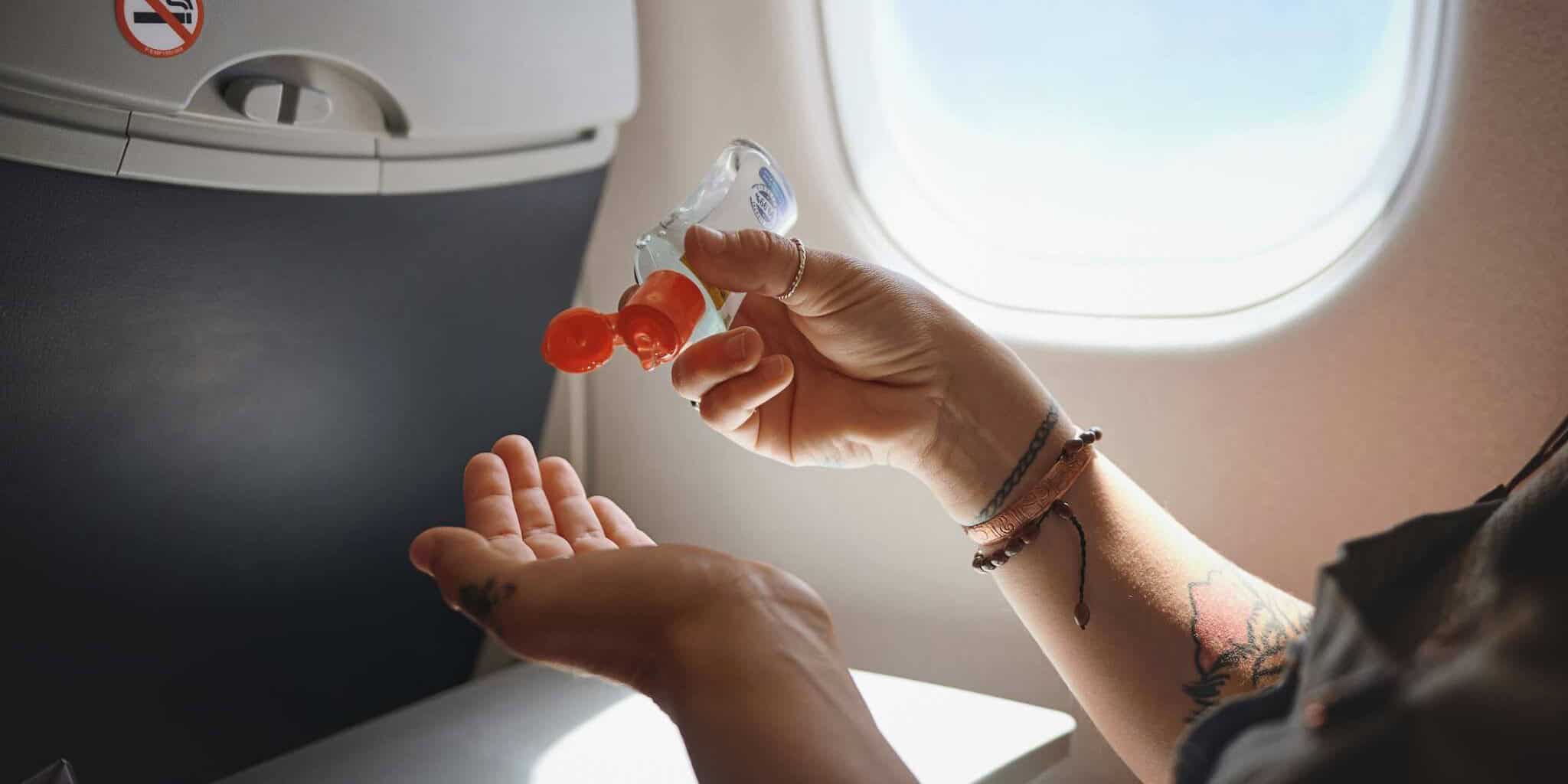 someone using hand sanitizer on a plane as part of their plan for staying healthy while traveling