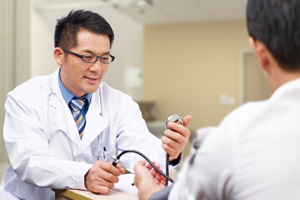 a doctor checking the blood pressure of a patient, showing how expats can access Hong Kong healthcare 