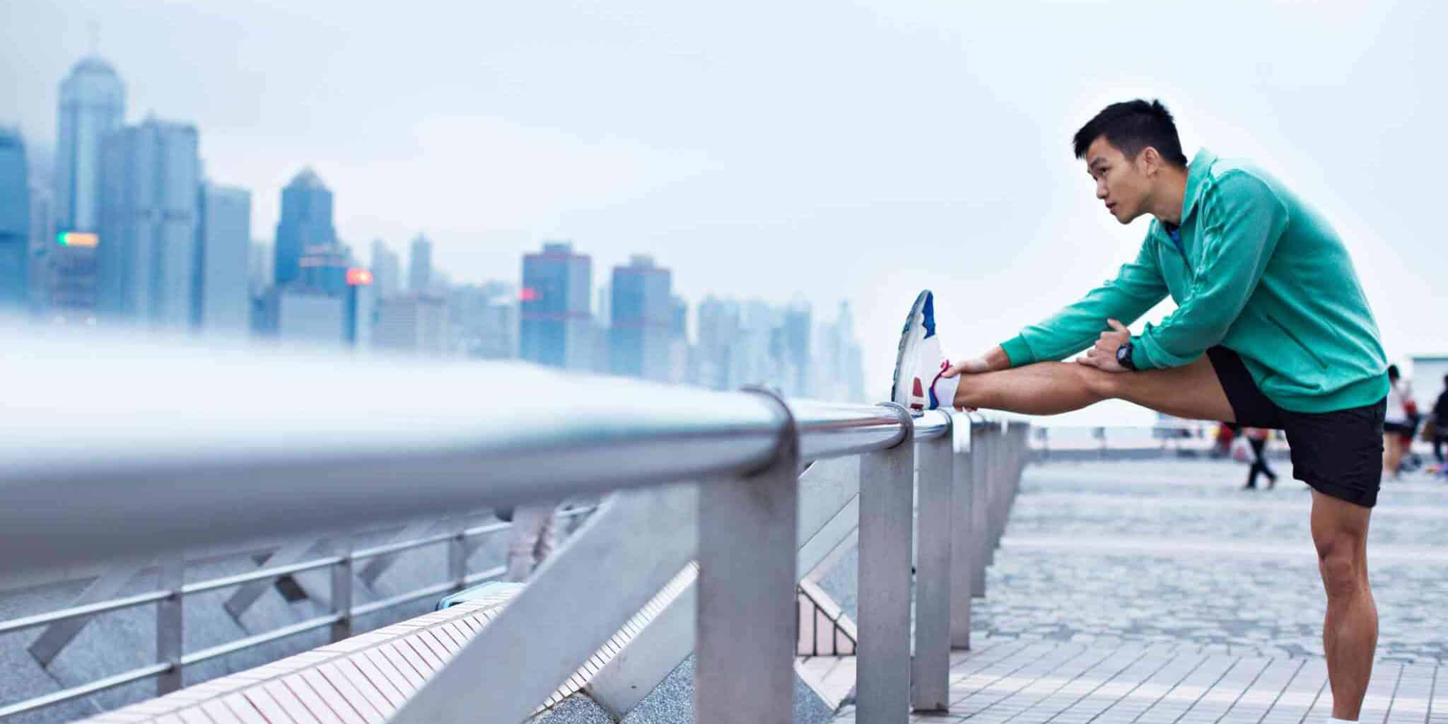 a man stretching during a jog in a city as part of his plan for staying healthy while traveling