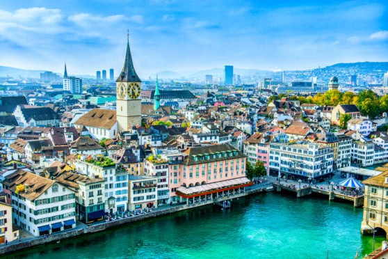 A vibrant aerial view of Zurich, Switzerland, showcasing colorful historic buildings, a river promenade, and scenic cityscape, emphasizing global insurance solutions for expatriates and international travelers.