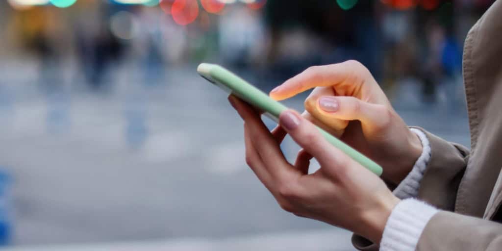 A close-up of a person using a smartphone outdoors, highlighting easy access to international health insurance information and services for global citizens as well as managing a bank account abroad.